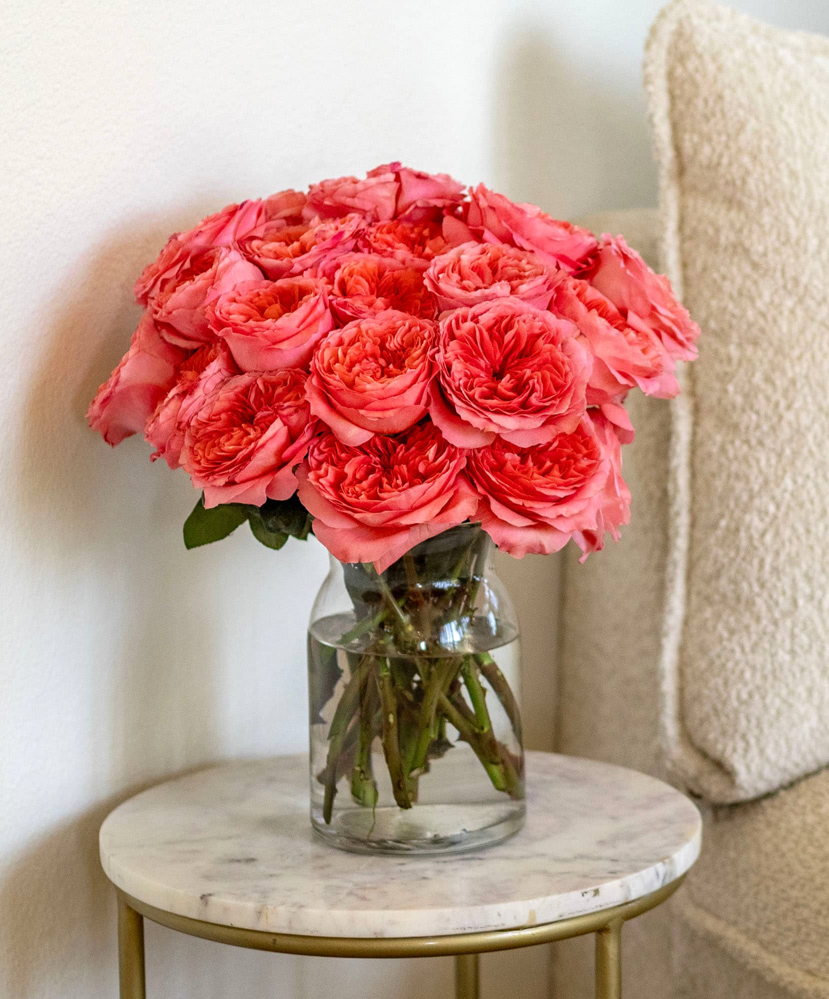 A stunning arrangement of vibrant pink roses in a clear glass vase on a stylish table.