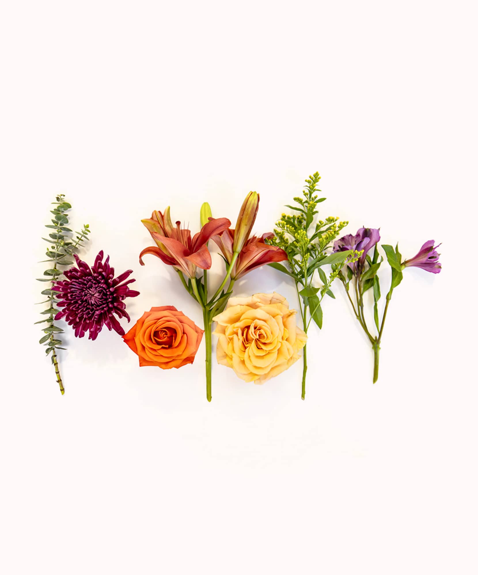 Vibrant floral arrangement featuring roses, lilies, and seasonal greenery on a light background.